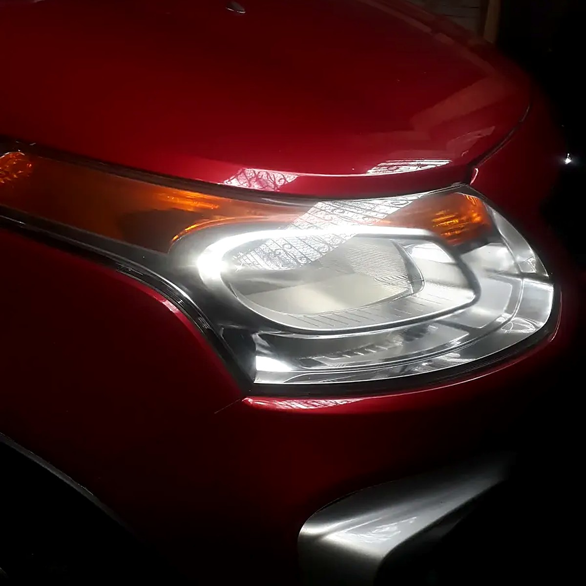 Farol com brilho após aplicação em carro vermelho